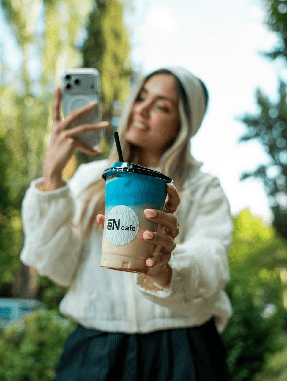 دختر جوان با نوشیدنی eN cafe در فضای سبز کافه